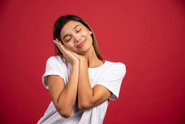 Giovane donna graziosa che posa sulla parete rossa.