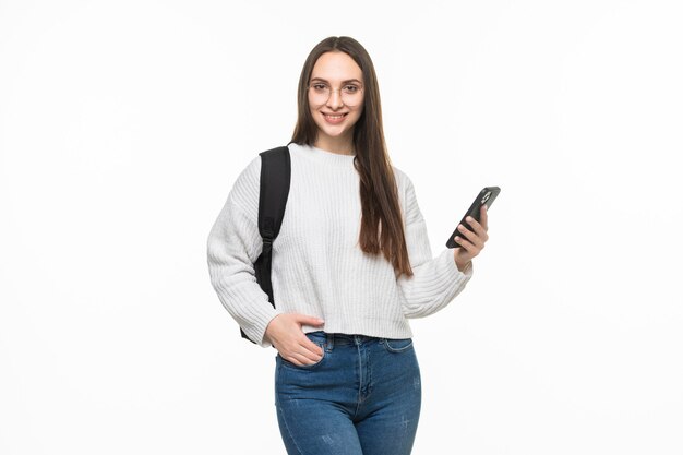 Giovane donna graziosa che utilizza il telefono cellulare isolato sul muro bianco