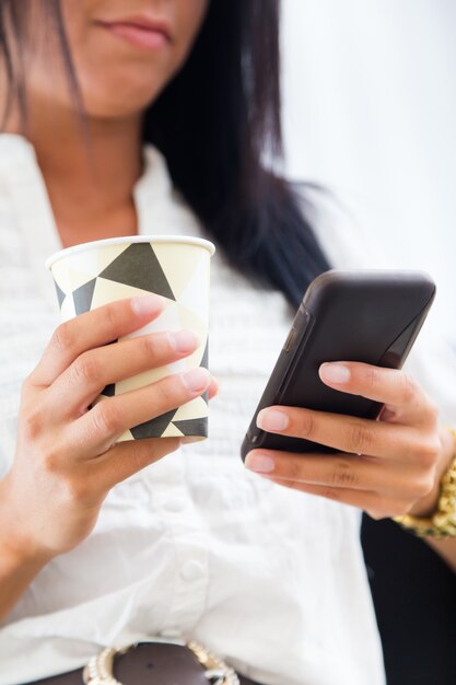 Giovane donna graziosa di affari con il telefono mobile nel suo ufficio.