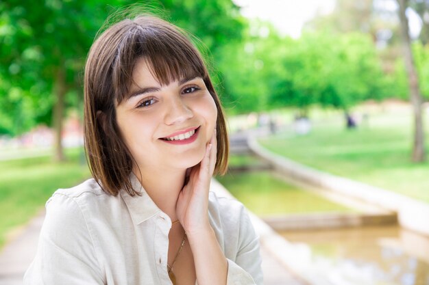 Giovane donna graziosa felice che gode della natura nel parco della città