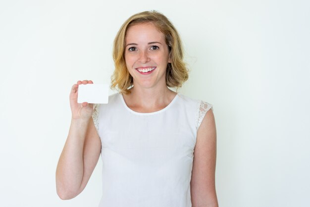 Giovane donna graziosa felice che mostra biglietto da visita in bianco