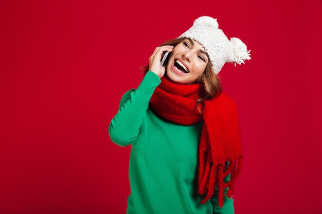 Giovane donna graziosa felice che parla dal telefono.