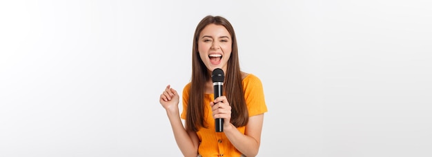 Giovane donna graziosa felice e motivata che canta una canzone con un microfono che presenta un evento o un havin