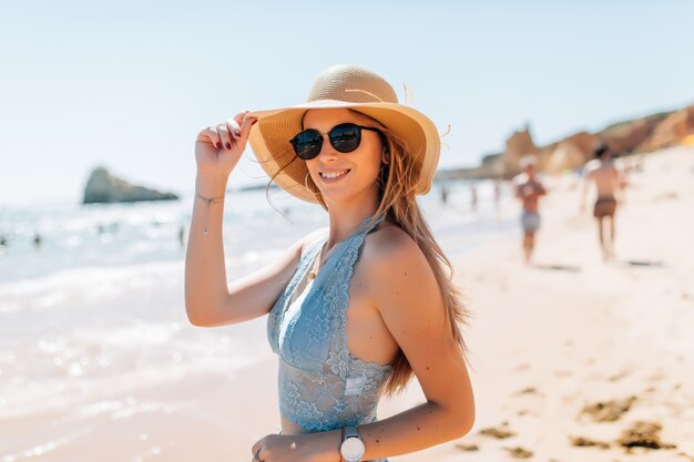 Giovane donna graziosa in cappello sulla spiaggia all'oceano