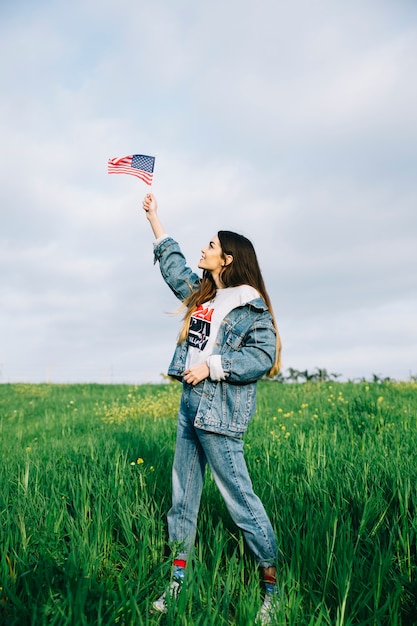 Giovane donna guardando piccola bandiera americana in braccio