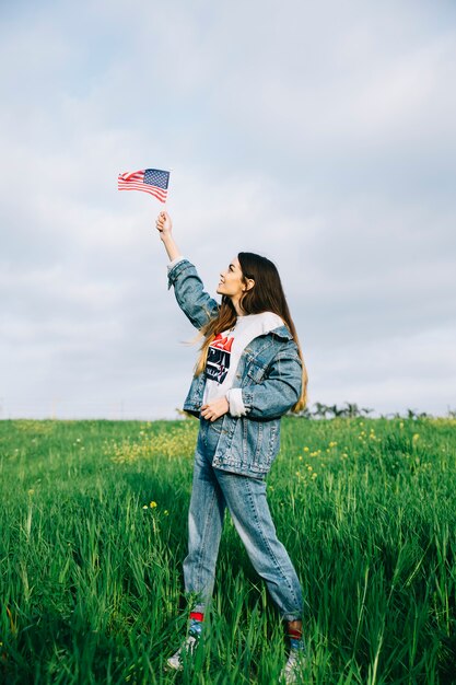 Giovane donna guardando piccola bandiera americana in braccio