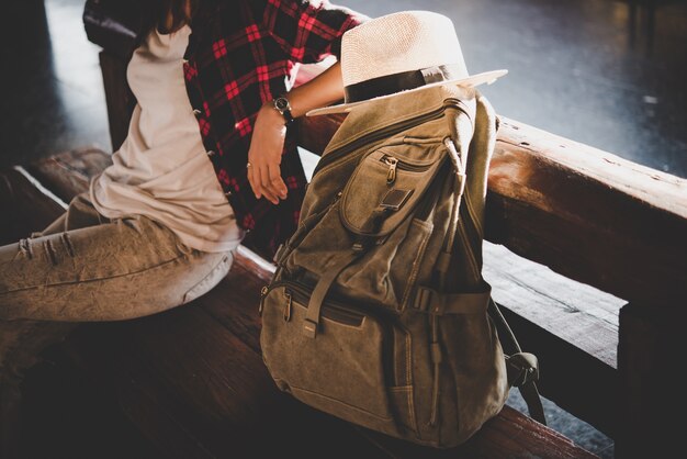 Giovane donna hipster turistica con zaino seduto nella stazione ferroviaria. Concetto turistico vacanza.