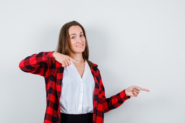 Giovane donna in abiti casual che punta a destra e sembra indecisa, vista frontale.