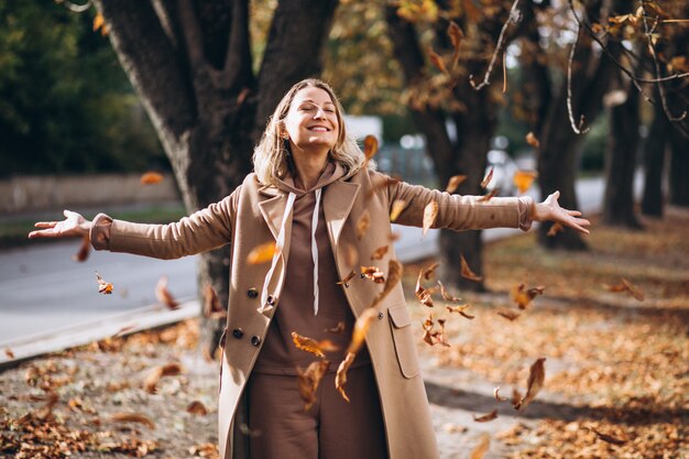 Giovane donna in abito beige fuori in un parco in autunno