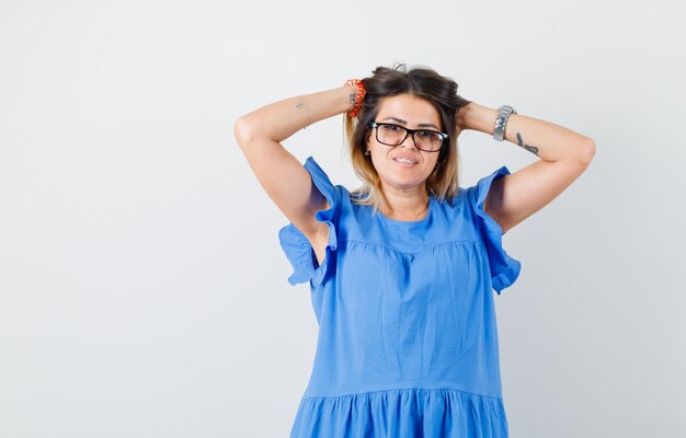 Giovane donna in abito blu in posa mentre si stringe la testa e sembra carina