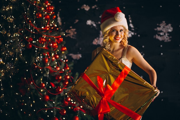 Giovane donna in abito con regali di Natale di albero di Natale