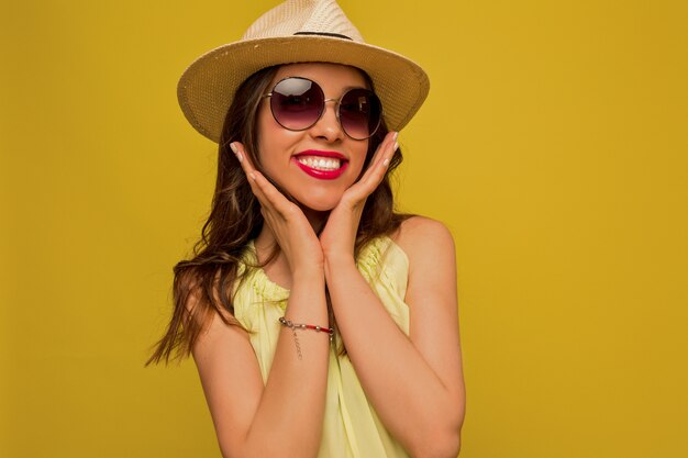 Giovane donna in abito giallo con cappello e occhiali da sole
