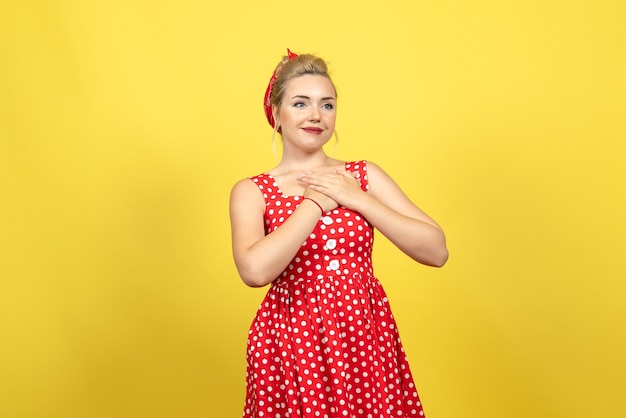 giovane donna in abito rosso a pois sorridente sul giallo