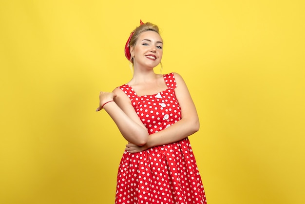 giovane donna in abito rosso a pois sorridente sul giallo