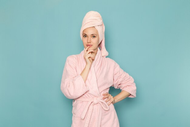 giovane donna in accappatoio rosa dopo la doccia in posa sul blu