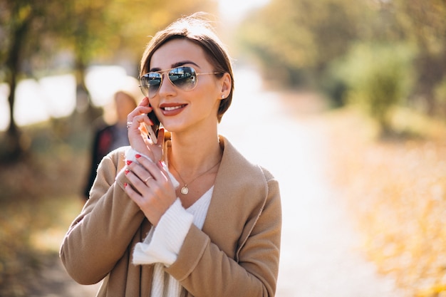 Giovane donna in autunno parco utilizzando il telefono