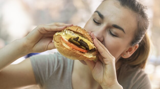 Giovane donna in caffè che mangia gustoso panino