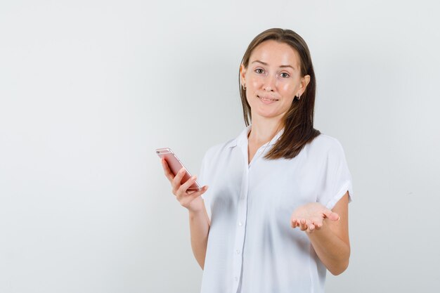 Giovane donna in camicetta bianca che discute di qualcosa e che sembra loquace