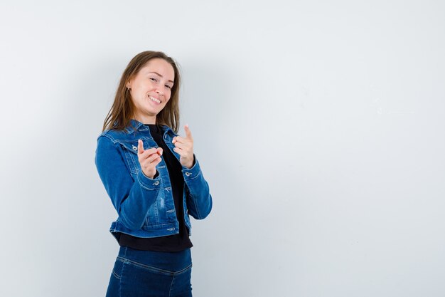 Giovane donna in camicetta che punta alla telecamera e sembra sicura, vista frontale.