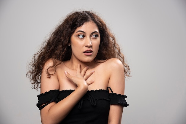 Giovane donna in camicetta nera con capelli ricci in posa. Foto di alta qualità