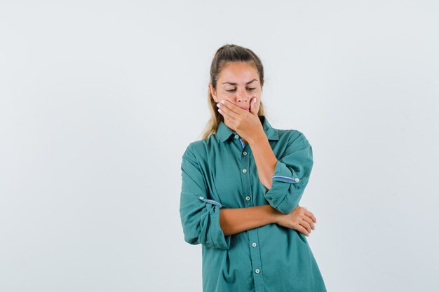 Giovane donna in camicetta verde che sbadiglia e che sembra assonnata