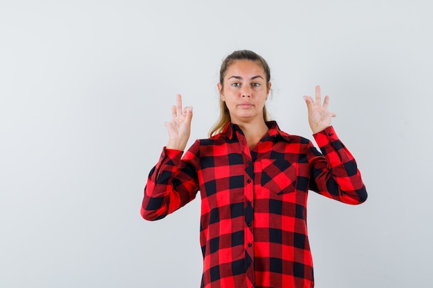 Giovane donna in camicia a quadri che mostra il gesto di meditazione e che sembra sicura