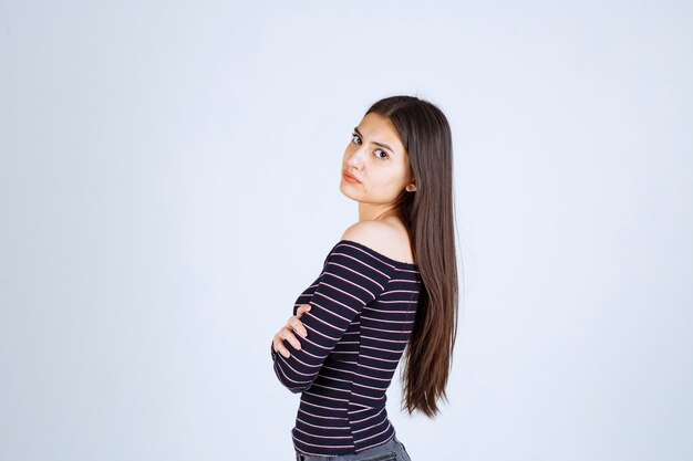 Giovane donna in camicia a strisce che attraversa le braccia e sembra seria