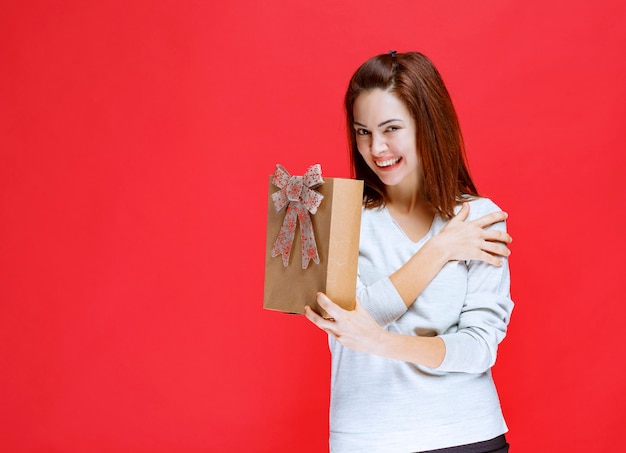 Giovane donna in camicia bianca con in mano una scatola regalo di cartone