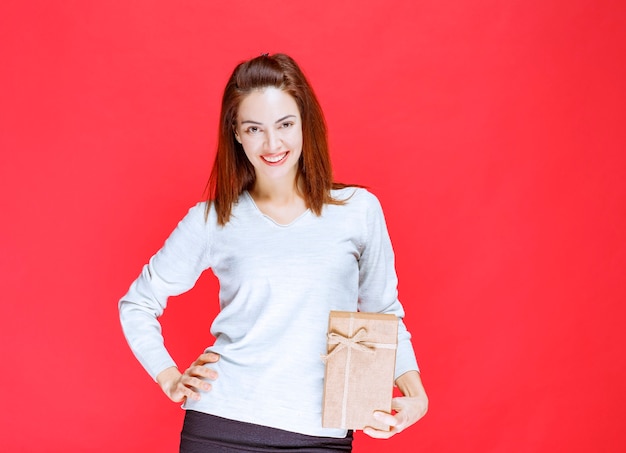 Giovane donna in camicia bianca con in mano una scatola regalo di cartone