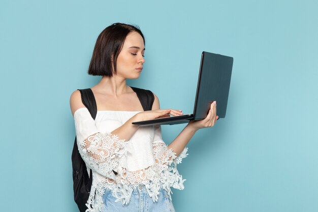 giovane donna in camicia bianca e borsa nera con laptop sul blu