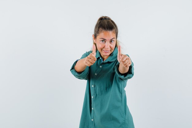 Giovane donna in camicia blu che mostra il pollice in su e sembra ottimista