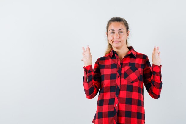 Giovane donna in camicia casual che mostra gesto di meditazione e guardando pensieroso, vista frontale.