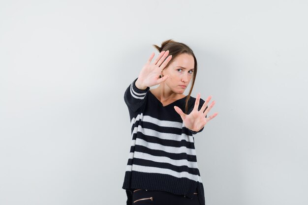 Giovane donna in camicia casual che mostra il gesto di arresto e che sembra seria