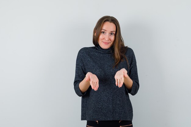 Giovane donna in camicia che mostra le palme vuote e che sembra positiva