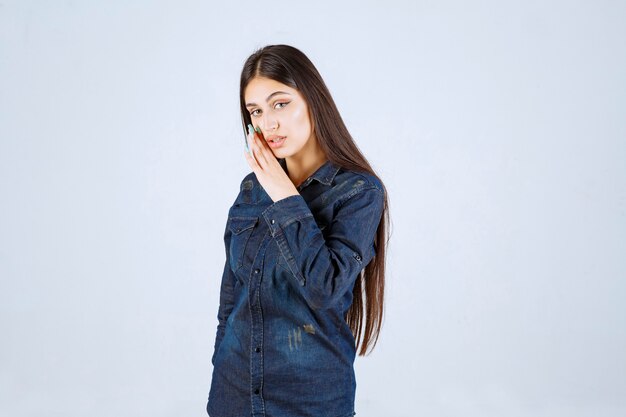 Giovane donna in camicia di jeans che bisbiglia e spettegola