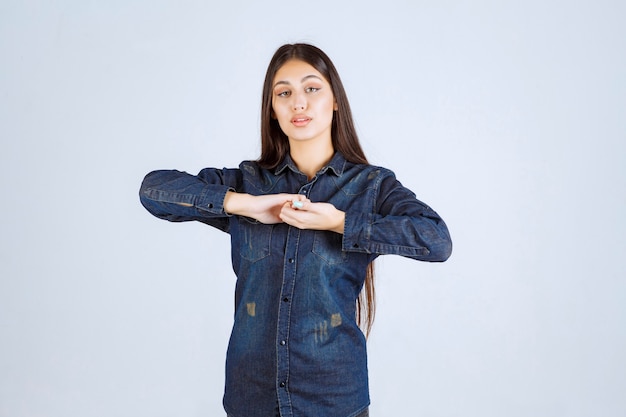 Giovane donna in camicia di jeans che dà pose neutre senza reazioni