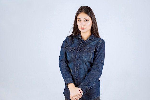 Giovane donna in camicia di jeans che dà pose neutre senza reazioni