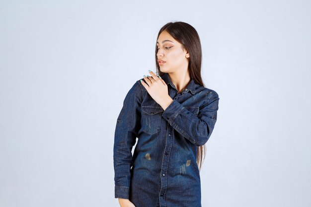 Giovane donna in camicia di jeans che dà pose neutre senza reazioni