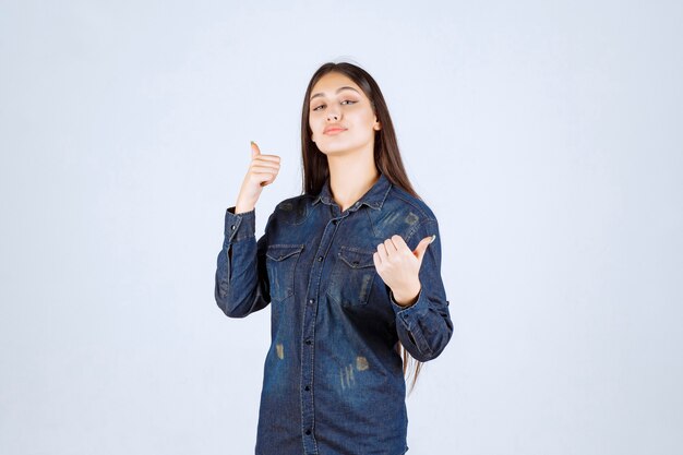 Giovane donna in camicia di jeans che mostra il segno positivo della mano