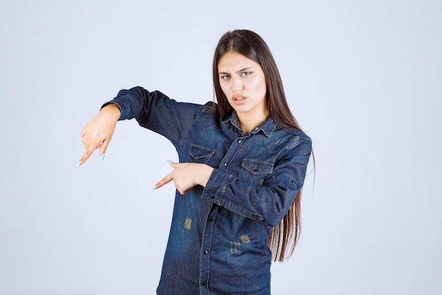 Giovane donna in camicia di jeans rivolta verso il basso