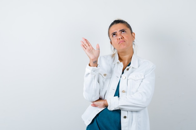 Giovane donna in camicia, giacca bianca che agita la mano per salutare e sembra insoddisfatta, vista frontale.