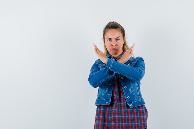 Giovane donna in camicia, giacca che mostra il gesto di arresto e sembra fiduciosa, vista frontale.