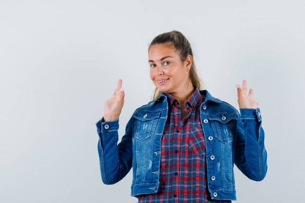 Giovane donna in camicia, giacca che mostra il gesto di meditazione e che sembra allegra, vista frontale.