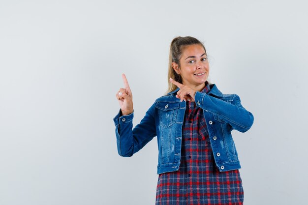 Giovane donna in camicia, giacca rivolta verso l'alto e guardando fiducioso, vista frontale.