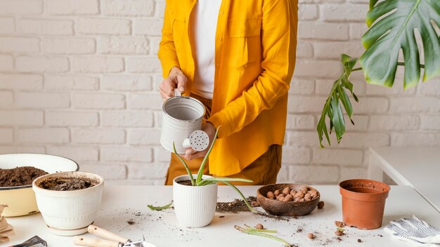 Giovane donna in camicia gialla giardinaggio a casa