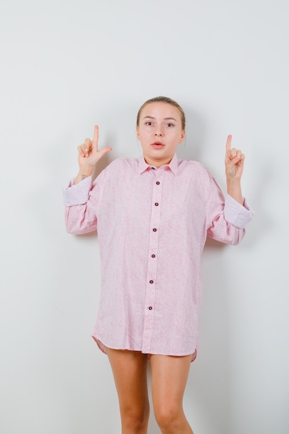Giovane donna in camicia rosa rivolta verso l'alto e guardando confuso