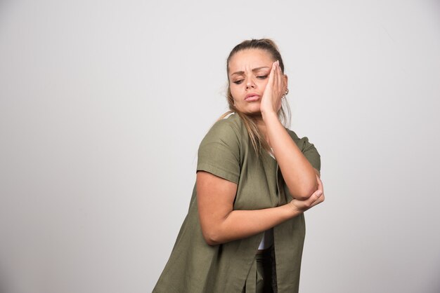 Giovane donna in camicia verde che ha mal di denti.