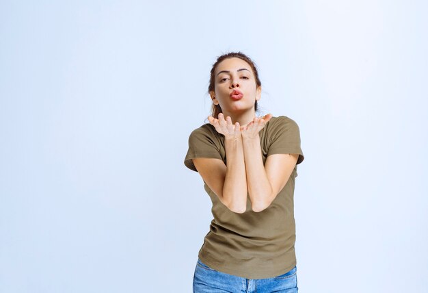 Giovane donna in camicia verde che invia amore e flirta