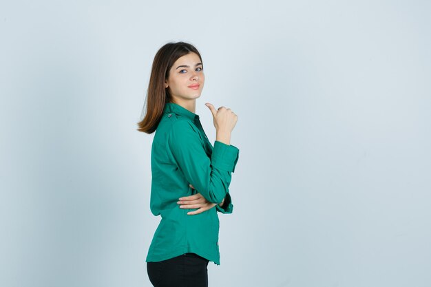Giovane donna in camicia verde che mostra il pollice in su e sembra soddisfatta.