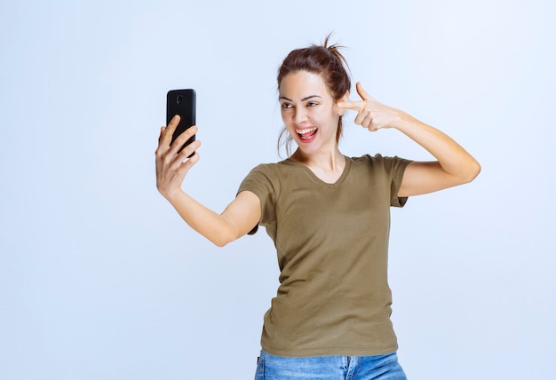 Giovane donna in camicia verde che prende il suo selfie e sembra motivata